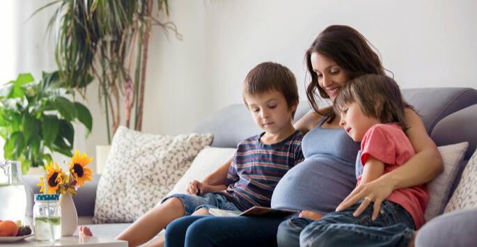 Pregnant woman reads with her two other kids