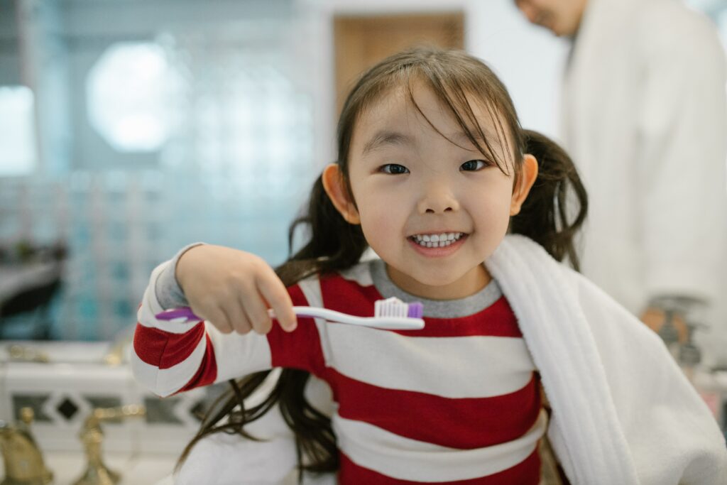 A cheerful child while cleaning her teeth