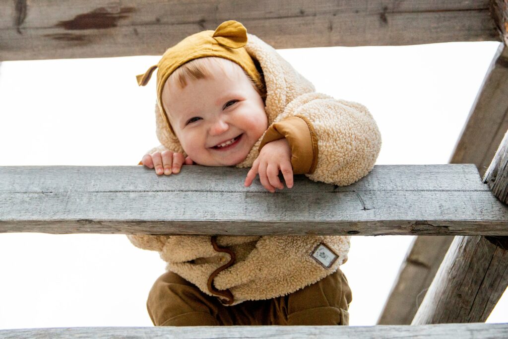 A smiling baby climbs on a playground