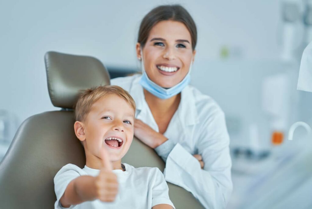 A little boy with his dentist smiling and giving a thumbs up