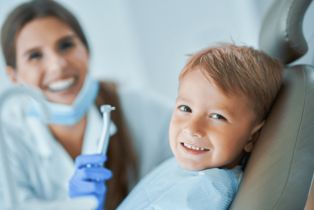 A young boy and a dental hygienist smiling at the camera
