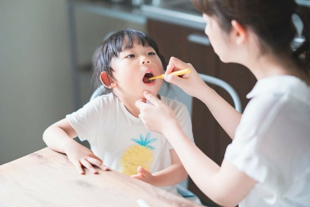 A parent checking her daughter’s teeth for tooth decay and its effects