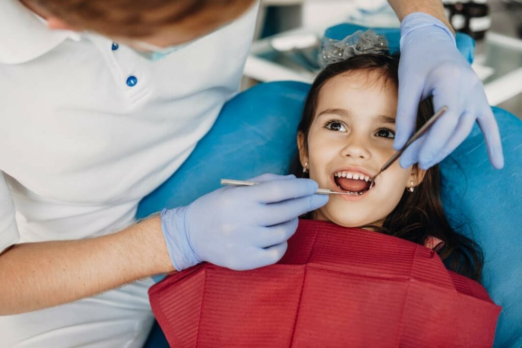 A young girl getting her teeth checked by a dentist