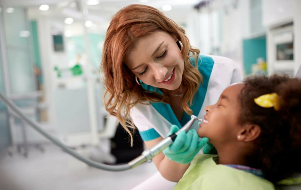 A dentist and a kid during teeth cleaning